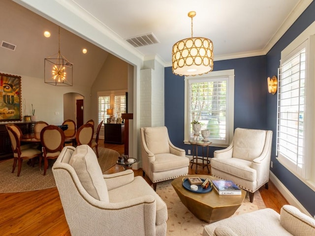 6319 Mccommas Blvd, Dallas, TX 75214 - living room featuring healthy amount of natural light, a chandelier, wood finished floors, arched walkways, and ornamental molding