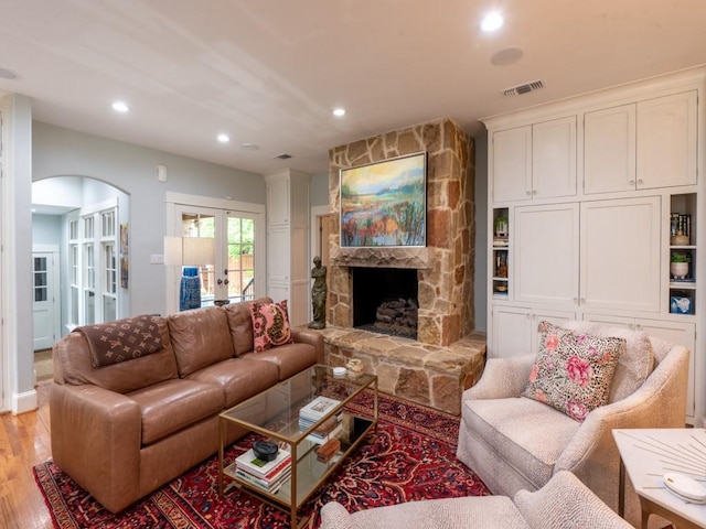 6319 Mccommas Blvd, Dallas, TX 75214 - living room featuring french doors, arched walkways, light wood-type flooring, recessed lighting, and a fireplace