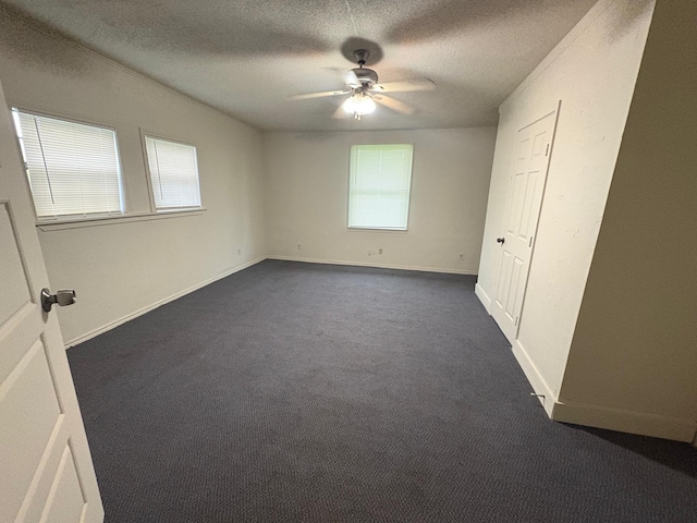 6827 Ensign Rd, Ennis, TX 75119 - unfurnished bedroom featuring multiple windows, a textured ceiling, dark carpet, baseboards, and a ceiling fan