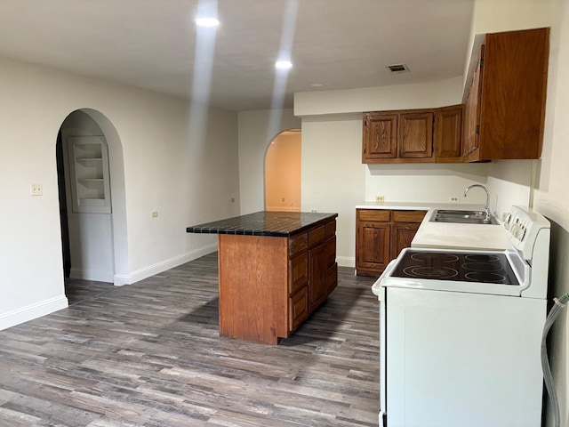6827 Ensign Rd, Ennis, TX 75119 - kitchen featuring white range with electric stovetop, arched walkways, a sink, a kitchen island, and brown cabinets