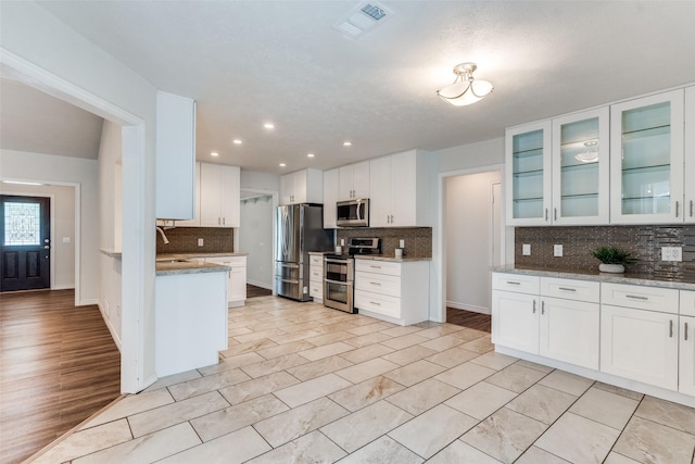 2309 Merrimac Dr, Plano, TX 75075 - kitchen featuring stainless steel appliances, decorative backsplash, white cabinets, glass insert cabinets, and recessed lighting