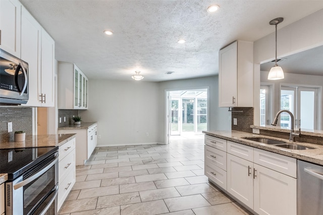 2309 Merrimac Dr, Plano, TX 75075 - kitchen featuring a sink, stainless steel appliances, backsplash, light stone countertops, and healthy amount of natural light
