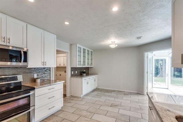 2309 Merrimac Dr, Plano, TX 75075 - kitchen with appliances with stainless steel finishes, tasteful backsplash, baseboards, light stone countertops, and glass insert cabinets