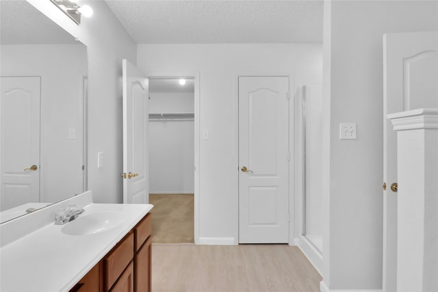 8300 Southern Prairie Dr, Fort Worth, TX 76123 - bathroom with vanity, a textured ceiling, wood finished floors, a shower, and baseboards