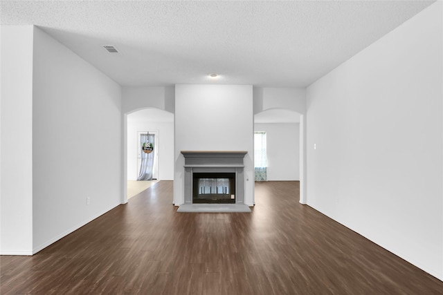 8300 Southern Prairie Dr, Fort Worth, TX 76123 - unfurnished living room with arched walkways, dark wood-style flooring, a textured ceiling, and a multi sided fireplace