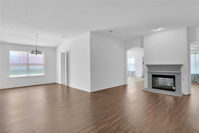 8300 Southern Prairie Dr, Fort Worth, TX 76123 - unfurnished living room featuring arched walkways, a chandelier, dark wood-type flooring, healthy amount of natural light, and a textured ceiling