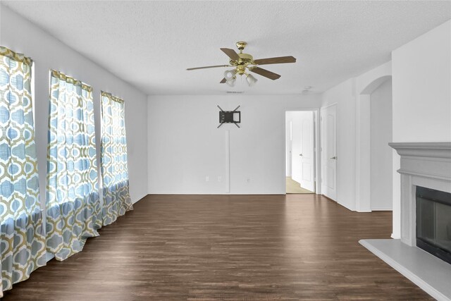 8300 Southern Prairie Dr, Fort Worth, TX 76123 - unfurnished living room featuring a ceiling fan, wood finished floors, a glass covered fireplace, a textured ceiling, and arched walkways