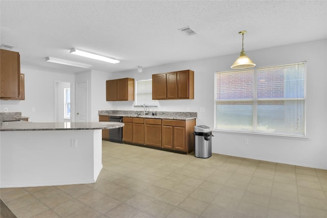 8300 Southern Prairie Dr, Fort Worth, TX 76123 - kitchen featuring dishwasher, a textured ceiling, brown cabinetry, light stone countertops, and hanging light fixtures
