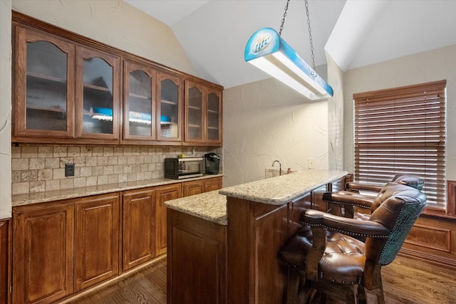 1205 Platte Dr, Mansfield, TX 76063 - kitchen featuring vaulted ceiling, dark wood-style flooring, light stone countertops, glass insert cabinets, and decorative backsplash