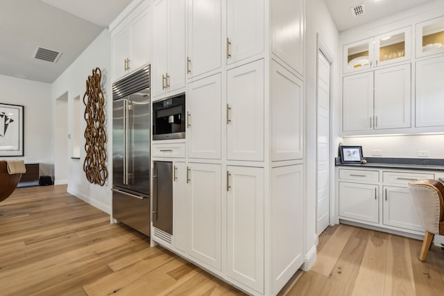 32 Katie Ln, Trophy Club, TX 76262 - kitchen with stainless steel built in fridge, light wood-style flooring, white cabinets, and dark countertops