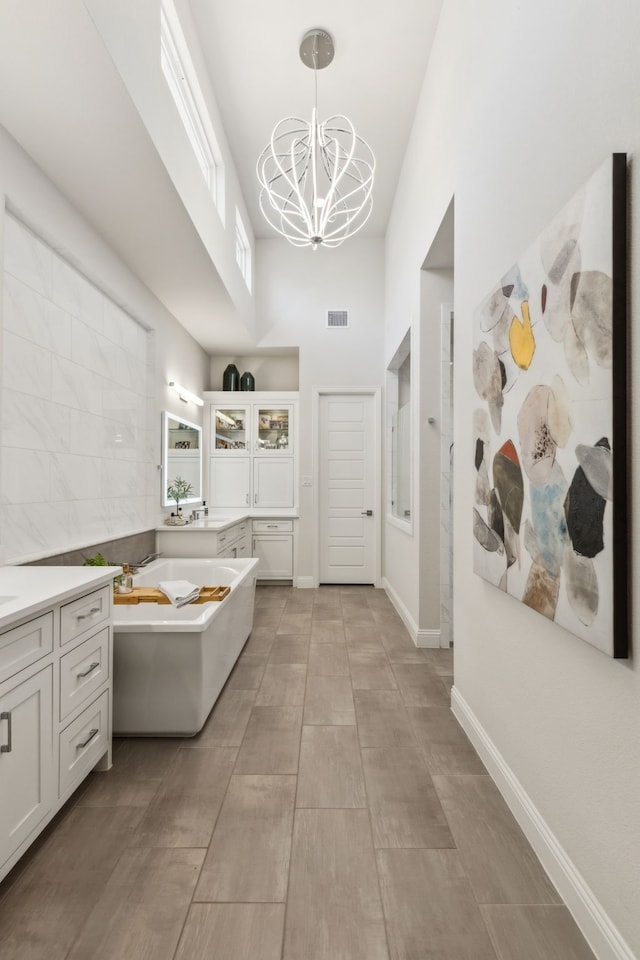 32 Katie Ln, Trophy Club, TX 76262 - bathroom featuring a high ceiling, a garden tub, a chandelier, and vanity