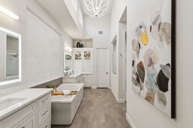 32 Katie Ln, Trophy Club, TX 76262 - full bathroom featuring a bath, two vanities, a high ceiling, a chandelier, and baseboards