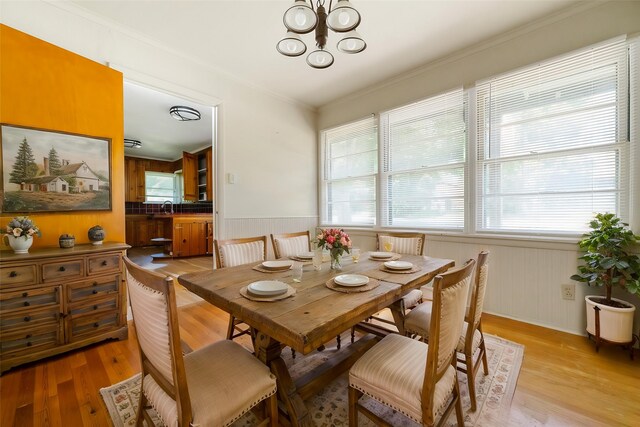 6908 Park Place Dr, Richland Hills, TX 76118 - dining space with a chandelier, light wood-type flooring, crown molding, a wainscoted wall, and wooden walls