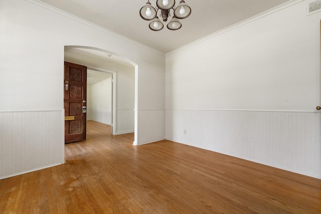 6908 Park Place Dr, Richland Hills, TX 76118 - spare room featuring arched walkways, wood finished floors, a wainscoted wall, a chandelier, and ornamental molding