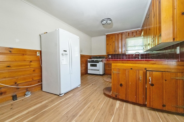 6908 Park Place Dr, Richland Hills, TX 76118 - kitchen featuring white appliances, brown cabinets, crown molding, light wood finished floors, and wood walls