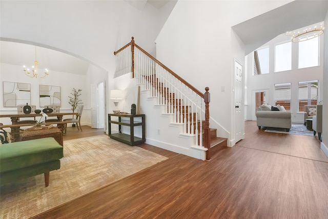 3601 Aqua Springs Dr, Plano, TX 75025 - living area with a chandelier, a high ceiling, stairs, wood finished floors, and arched walkways