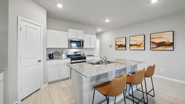 8417 Stout Dr, Fort Worth, TX 76131 - kitchen featuring appliances with stainless steel finishes, a sink, white cabinetry, recessed lighting, and a kitchen bar