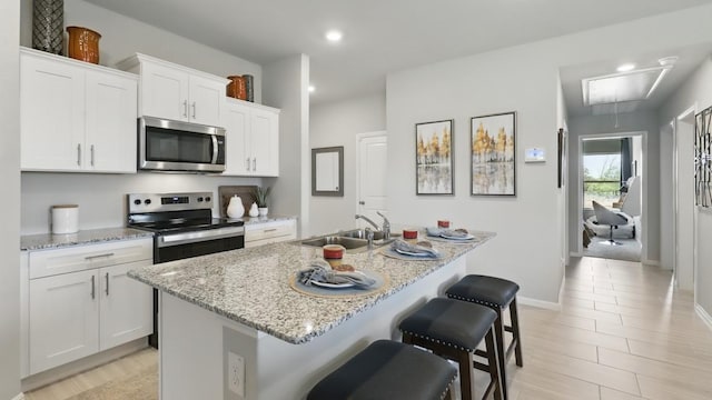 857 Cedarbrook, Fort Worth, TX 76131 - kitchen with stainless steel appliances, a sink, an island with sink, white cabinets, and light stone countertops