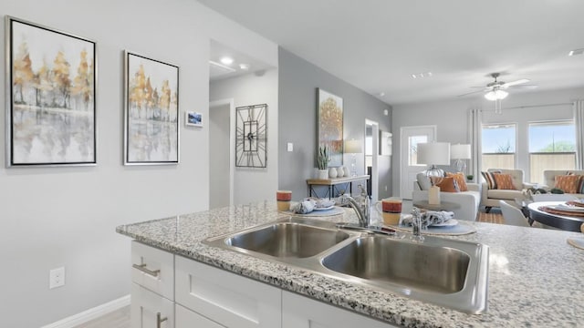 857 Cedarbrook, Fort Worth, TX 76131 - kitchen featuring a sink, white cabinetry, baseboards, ceiling fan, and light stone counters