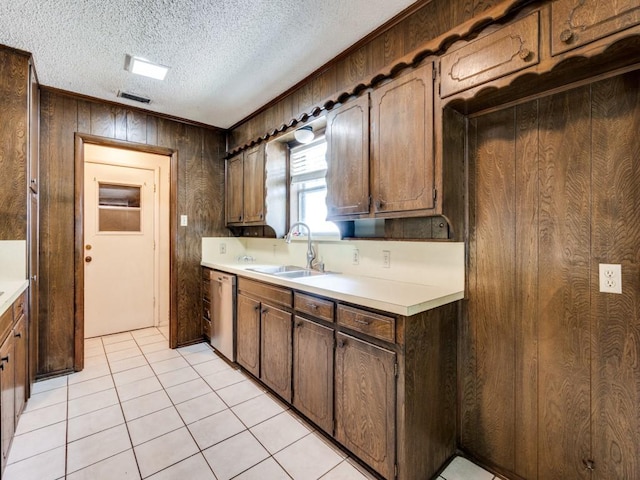 809 S Ridgeway Dr, Cleburne, TX 76033 - kitchen featuring a sink, stainless steel dishwasher, light countertops, wood walls, and light tile patterned flooring