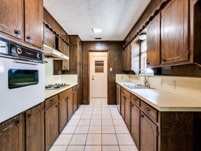 809 S Ridgeway Dr, Cleburne, TX 76033 - kitchen with white appliances, light countertops, under cabinet range hood, a sink, and a textured ceiling