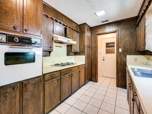 809 S Ridgeway Dr, Cleburne, TX 76033 - kitchen featuring white oven, under cabinet range hood, stovetop, light countertops, and wooden walls