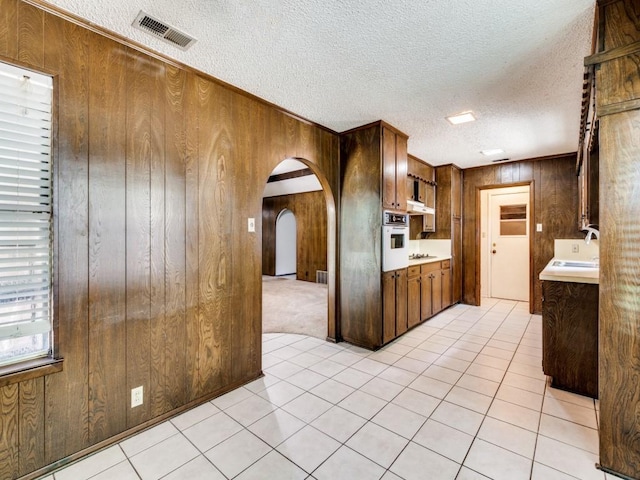 809 S Ridgeway Dr, Cleburne, TX 76033 - kitchen featuring wooden walls, oven, arched walkways, light countertops, and a sink