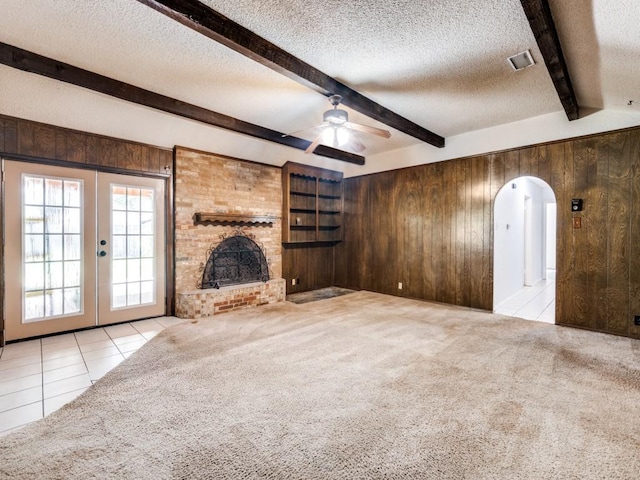 809 S Ridgeway Dr, Cleburne, TX 76033 - unfurnished living room featuring wood walls, arched walkways, beamed ceiling, a textured ceiling, and carpet