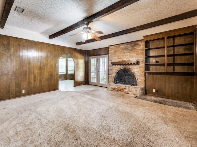 809 S Ridgeway Dr, Cleburne, TX 76033 - unfurnished living room featuring a textured ceiling, wooden walls, beam ceiling, ceiling fan, and carpet flooring