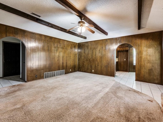 809 S Ridgeway Dr, Cleburne, TX 76033 - tiled empty room with arched walkways, beam ceiling, wooden walls, ceiling fan, and a textured ceiling