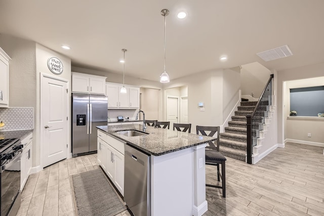 14613 Bootes Dr, Haslet, TX 76052 - kitchen featuring appliances with stainless steel finishes, a sink, a breakfast bar, light wood-style flooring, and recessed lighting