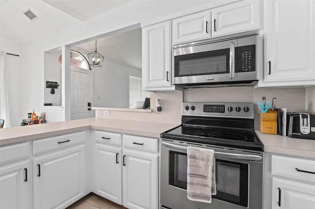 4100 Creekhollow Dr, Carrollton, TX 75010 - kitchen featuring appliances with stainless steel finishes, light countertops, a chandelier, and white cabinets