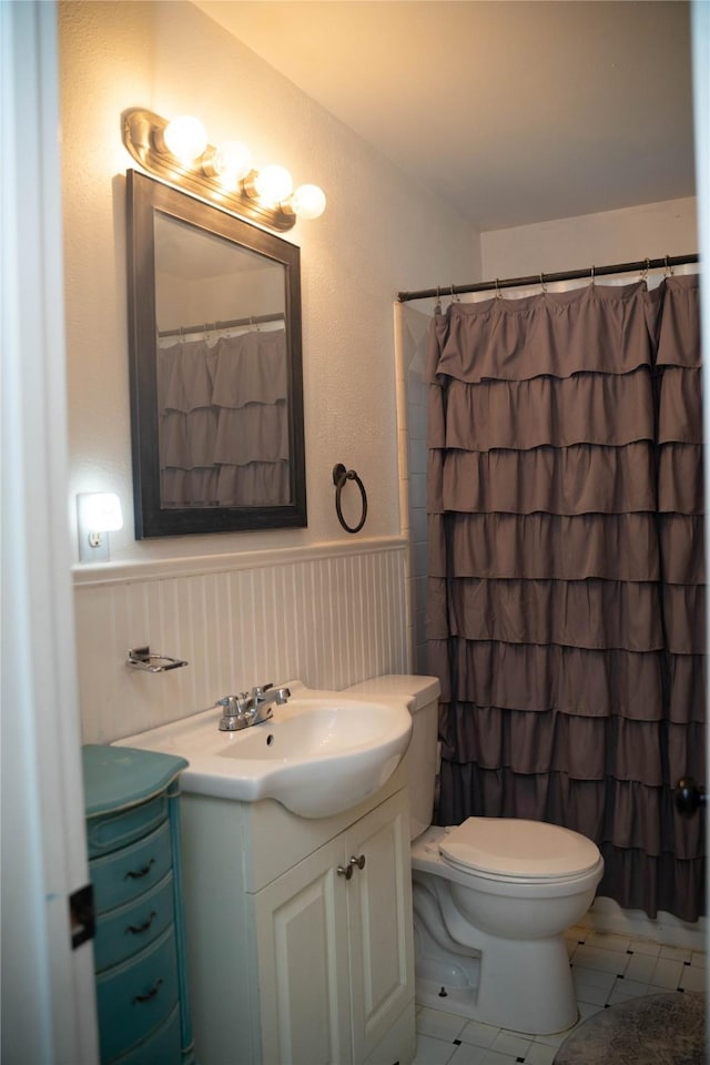 2204 13th St, Brownwood, TX 76801 - bathroom featuring vanity, wainscoting, toilet, tile patterned flooring, and curtained shower