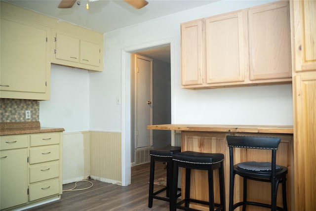 2204 13th St, Brownwood, TX 76801 - kitchen featuring dark wood-style floors, a ceiling fan, wainscoting, a breakfast bar area, and tasteful backsplash