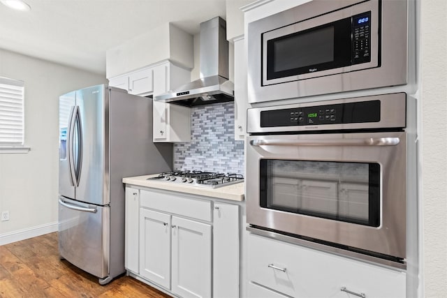 3806 Rainier St, Irving, TX 75062 - kitchen with wall chimney exhaust hood, appliances with stainless steel finishes, white cabinetry, light wood finished floors, and tasteful backsplash