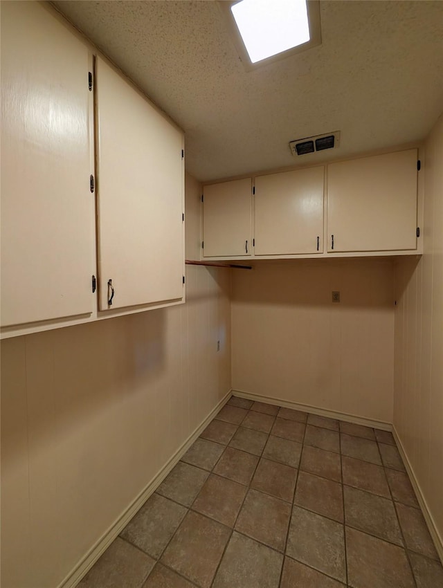 10335 Nolan Dr, Tyler, TX 75709 - washroom featuring a textured ceiling, baseboards, cabinet space, and tile patterned floors