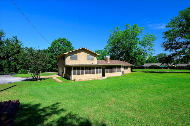10335 Nolan Dr, Tyler, TX 75709 - view of side of home with a sunroom, a lawn, a chimney, and a garage
