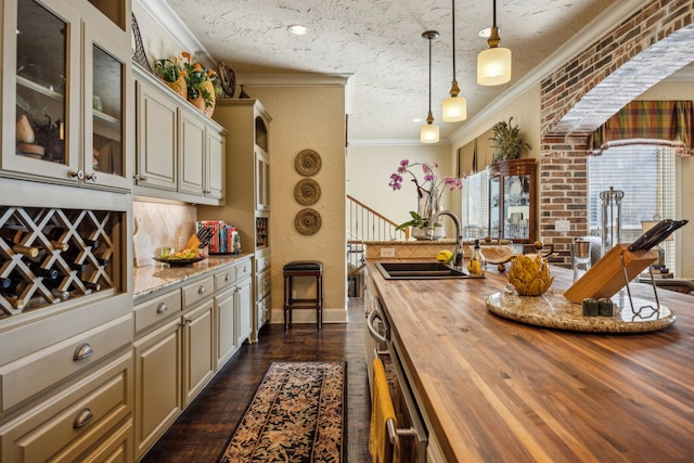 2590 King Arthur Blvd, Lewisville, TX 75056 - kitchen with wood counters, ornamental molding, a sink, dark wood finished floors, and glass insert cabinets