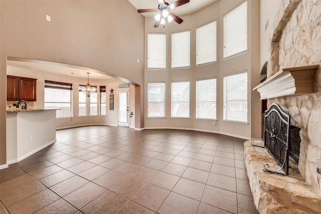 201 Barkley Dr, Hickory Creek, TX 75065 - unfurnished living room featuring ceiling fan, a chandelier, a stone fireplace, tile patterned flooring, and a towering ceiling