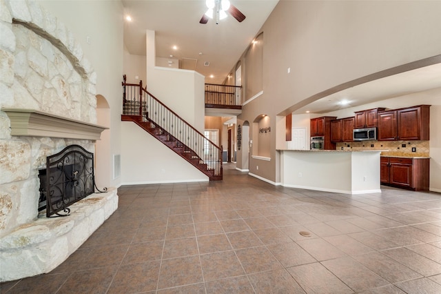 201 Barkley Dr, Hickory Creek, TX 75065 - unfurnished living room featuring a towering ceiling, arched walkways, ceiling fan, tile patterned floors, and a fireplace