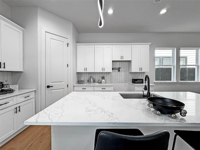 2419 Merlin St, Dallas, TX 75215 - kitchen with white cabinetry, backsplash, and light stone countertops