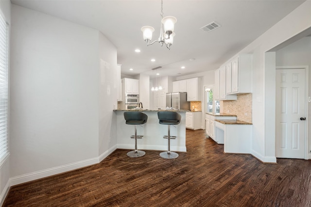 2145 Tartan Trl, Highland Village, TX 75077 - kitchen with appliances with stainless steel finishes, a chandelier, dark wood-style floors, decorative backsplash, and a peninsula