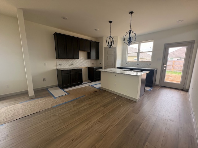 4033 Rimfire Rd, Waco, TX 76705 - kitchen featuring backsplash, a center island, light wood-style floors, light stone countertops, and recessed lighting
