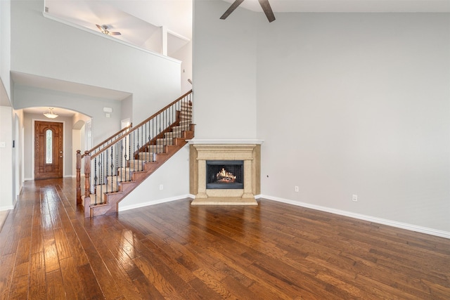 459 Bristol St, Roanoke, TX 76262 - unfurnished living room with a ceiling fan, arched walkways, wood-type flooring, stairway, and a towering ceiling