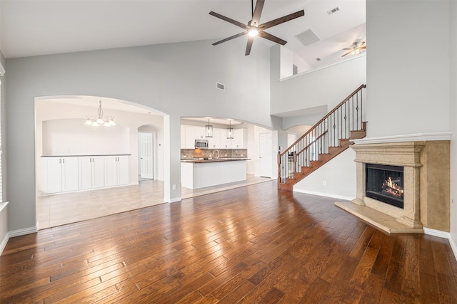 459 Bristol St, Roanoke, TX 76262 - unfurnished living room with a ceiling fan, a glass covered fireplace, a chandelier, hardwood / wood-style flooring, and arched walkways