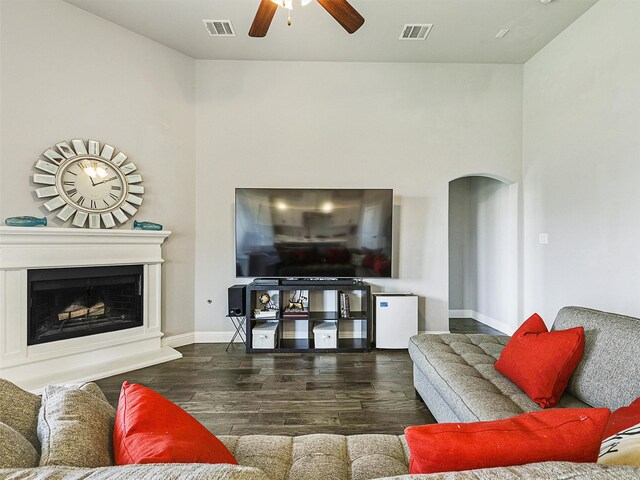 9713 Excursion Dr, Little Elm, TX 75068 - living room featuring arched walkways, a ceiling fan, wood finished floors, a fireplace with raised hearth, and baseboards
