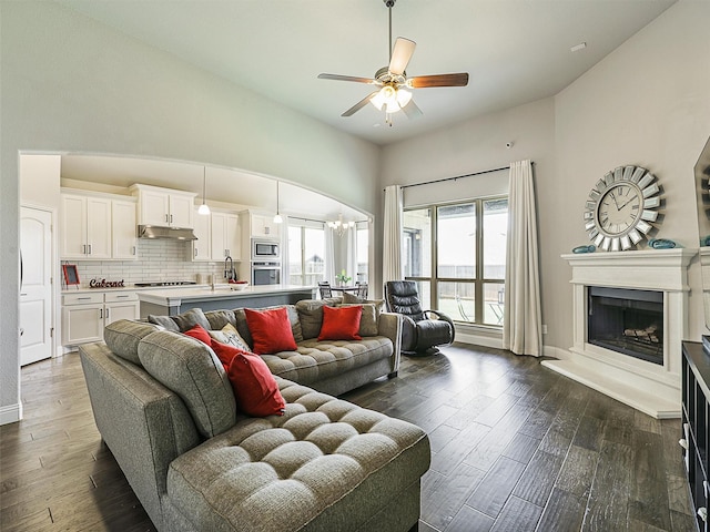 9713 Excursion Dr, Little Elm, TX 75068 - living area with a ceiling fan, a fireplace with raised hearth, dark wood-type flooring, a chandelier, and baseboards