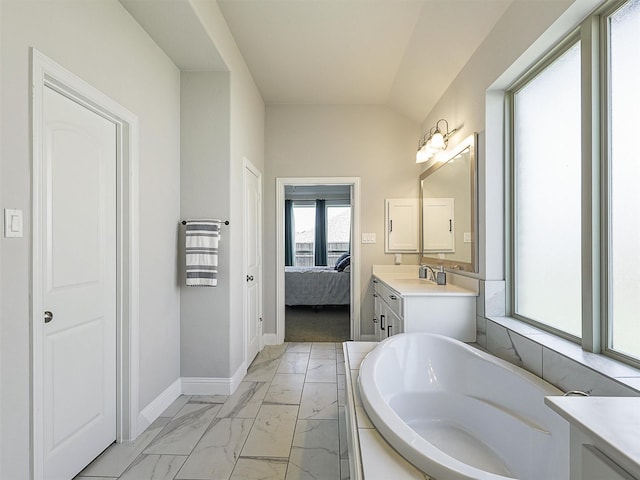 9713 Excursion Dr, Little Elm, TX 75068 - ensuite bathroom with marble look tiles, a garden tub, vanity, baseboards, and lofted ceiling