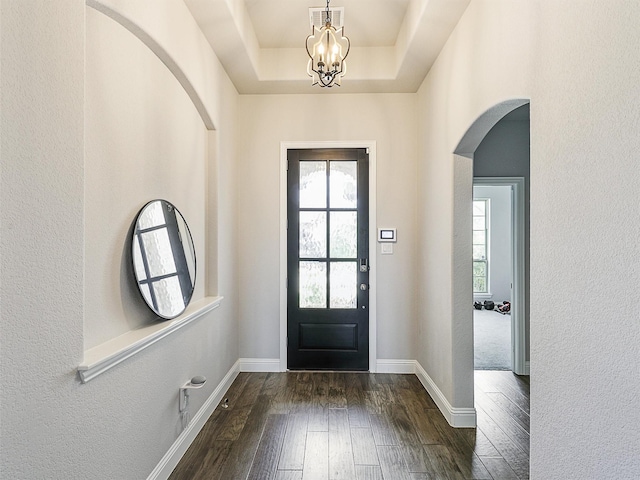 9713 Excursion Dr, Little Elm, TX 75068 - foyer entrance featuring arched walkways, dark wood-type flooring, a chandelier, a textured wall, and baseboards