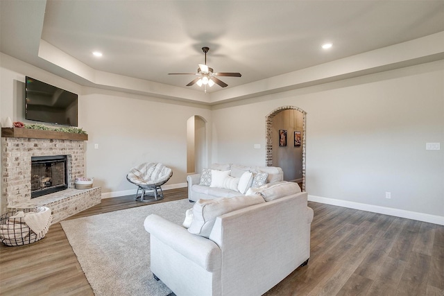 9405 Wildcat Rdg, Godley, TX 76044 - living room featuring arched walkways, baseboards, dark wood finished floors, a ceiling fan, and a brick fireplace